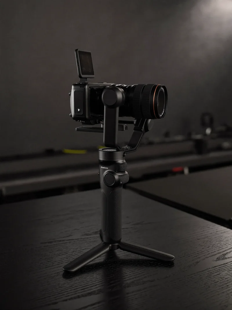 Gimbal-Stabilisator mit kompakter Kamera auf mattem dunklem Tisch